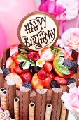 A chocolate cake with chocolate bars, wafer rolls and summer fruits for a birthday