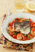 Fried sea bass on a bed of shrimps and tomatoes