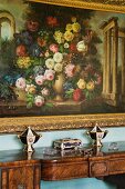 Floral painting with gilt frame above antique wooden console table