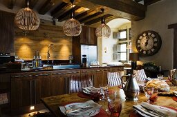 Finnish, designer pendant lamps made from wooden slats above kitchen counter and set dining table in rustic ambiance