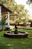 Fountain with statue in garden of Indian residential house with colonial-style porch on pillars