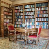 Historic library with antique table and chairs in front of a built in bookcase wall unit