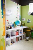 View through open doorway of work area with white desk top on shelving against green-painted wall