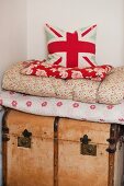 Cushion with Union Flag motif on stack of blankets on wooden trunk