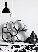 Regal aus verschieden grossen Metallringen zusammengebunden an der Wand und Vintage Hängelampen mit weißem und schwarzem Schirm