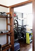 Shelves of machine components in foyer next to open door with view of vintage machinery beyond