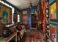 Interior with imaginative artworks on petrol blue walls; sofa opposite niche with draped curtains