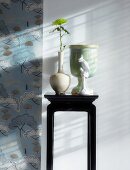 Kleiner Wandtisch mit Vasen neben Wandtapete mit floralem Muster im chinesischen Stil