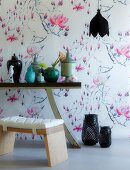 Wallpaper with airy pattern of magnolias; Chinese vases on console table in foreground