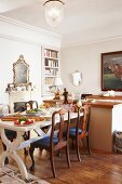 Set dining table and antique chairs in front of open fireplace