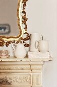 Detail of vintage fire surround with small, white china jugs on mantelpiece and splendid, gilt-framed mirror
