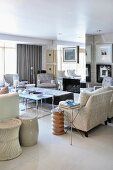 Living room crammed with pale upholstered furniture, tables and mirrored chimney breast