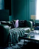 Velvet throw draped over green leather sofa in contemporary sitting room