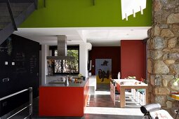 Modern kitchen with colourful red and spring green surfaces in open-plan interior