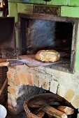 Old wood-fired oven with loaf on wooden peel