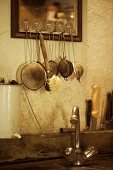 Siebe & Spülbürste hängen über rustikaler Spüle