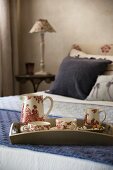 Tea set with toile de jouy pattern on tray on double bed
