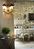 Grand dining table, Baroque chairs and lit candelabras in front of antique painting on rustic stone wall