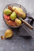 Assorted varieties of pear with a knife in a wire basket