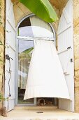 Billowing curtain at large, glazed round-arched window with wooden shutters (Chateau Maignaut)