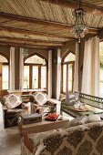 Wohnzimmer im marokkanischen Stil mit Holzbalkendecke, Spitzbogenfenster und bequemer Sitzlandschaft