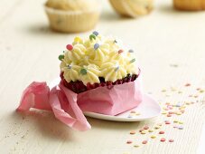A cupcake decorated with cream and sugar sprinkles