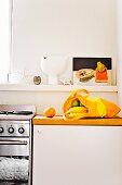 Küchenablage mit Stillleben; darunter eine gelbe Einkaufstasche mit frischem Obst