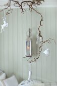 Glass and white china animal figurines hanging from branch as Advent decoration