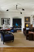 Art Deko Sessel mit königsblauem Bezug und schwarzem Gestell unter mehrarmiger Retro Deckenleuchte in herrschaftlichem Wohnzimmer