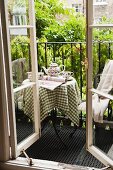 Teatime auf kleinem Stahlbalkon mit beranktem Geländer; Blick durch geöffnete Sprossenfenster