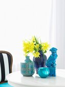 Bouquet of daffodils in blue ceramic vase on white table
