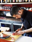 Japanese chef with sharp knife, filleting raw fish