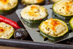 Grilled courgette slices with feta cheese on a baking tray