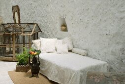 Schlichtes Tagesbett vor grossem Vogelkäfig auf Boden in Loggia eines mediterranen Wohnhauses