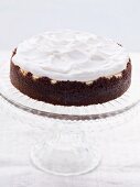 Chocolate cheesecake topped with cream on a cake stand