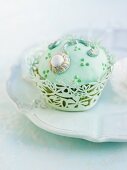 A cupcake with light green icing and decorations