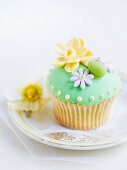 A cupcake decorated with green frosting and marzipan decorations