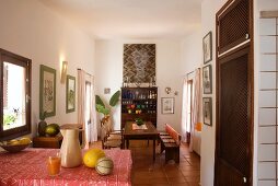 Open-plan interior with long dining table and crockery in modern dresser below modern picture on wall