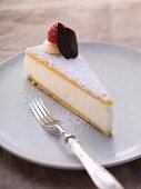 A slice of creamy cheese cake with icing sugar