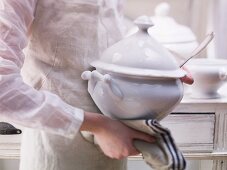 A person holding a soup tureen