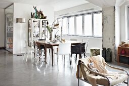 Loft-style interior with animal skin on vintage armchair in front of dining area with different chairs