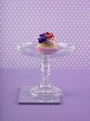 A raspberry cupcake on a cake stand