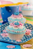 Light blue cupcakes decorated with pink flowers and sugar balls