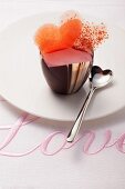 Rosa Praline mit Herzen auf Tisch mit Love-Stickerei