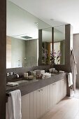 Huge mirror in modern bathroom with two sunken sinks in stone washstand