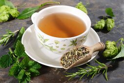 A cup of herbal tea surrounded by ingredients