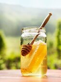 A jar of honey with a honeycomb and a honey spoon