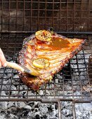 Pork ribs in a honey & soy marinade with lemon slices on the barbecue