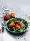 Rice dumplings filled with cheese on a mixed leaf salad