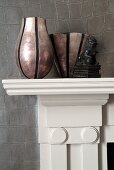 Different vases on mantelpiece against leather-covered wall